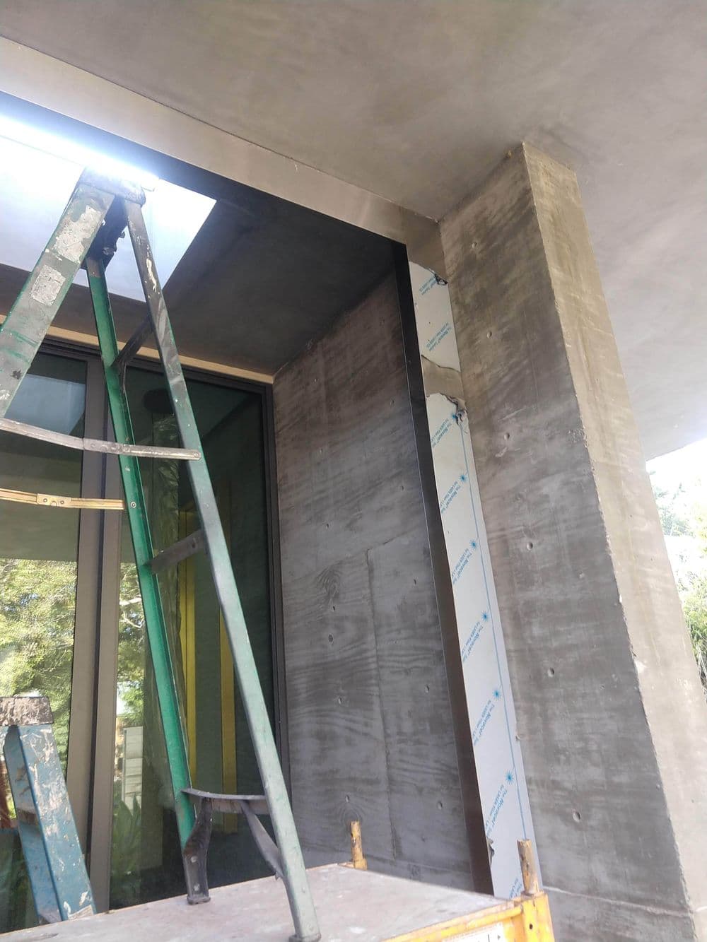 Construction site with scaffolding, showcasing a concrete column and large glass windows.