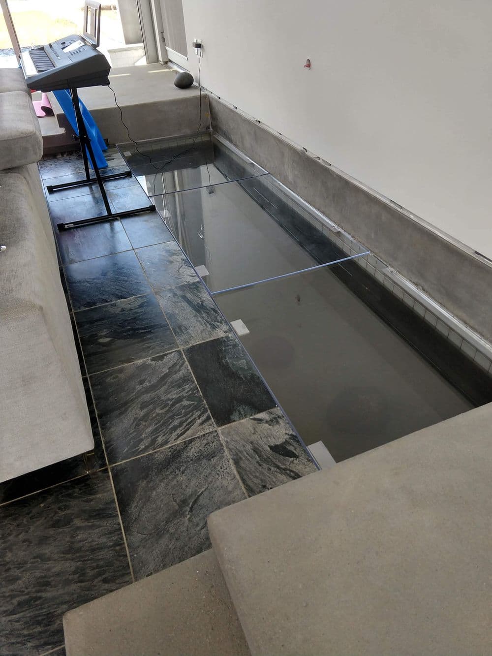 Modern living room with a glass floor design, revealing a space underneath. Stylish and contemporary.