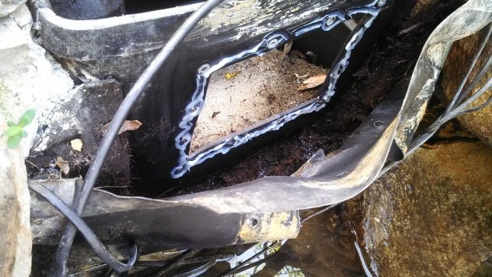 Close-up of a pond filter installation showing debris and water damage in the housing.
