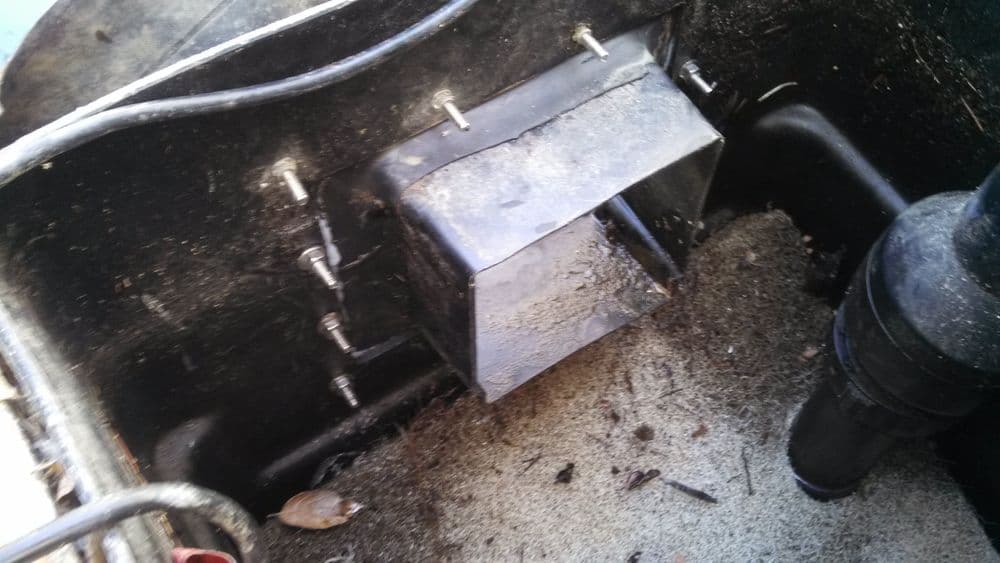 Close-up of a water pump compartment in a boat, showing metal housing and wiring details.