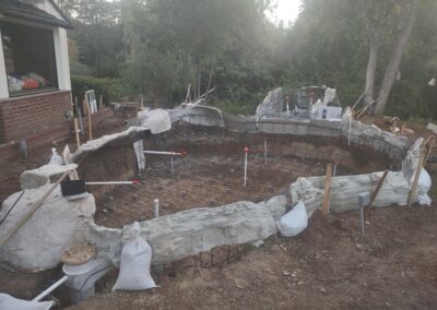 In-progress construction of a backyard pool with rebar and plumbing in place.