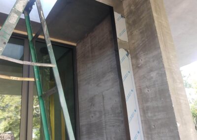 Construction site with scaffolding, showcasing a concrete column and large glass windows.