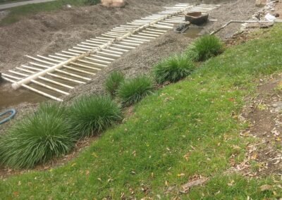 Construction site with workers assembling a gravel landscaping area and wooden framework.