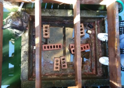 Bird's-eye view of a wooden structure over green water, featuring bricks and a net.