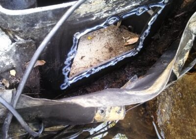 Close-up of a pond filter installation showing debris and water damage in the housing.