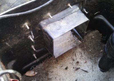 Close-up of a water pump compartment in a boat, showing metal housing and wiring details.