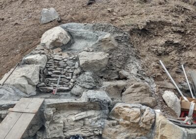 Construction site with stone steps and rocky terrain, showcasing building materials and tools.