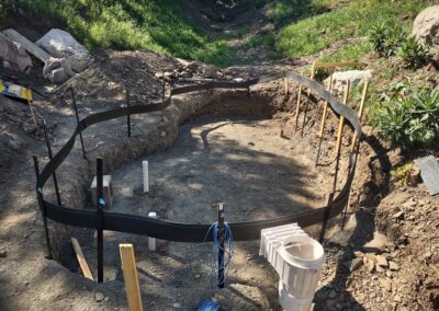 Excavated area with framing for foundation and plumbing in a construction site.