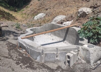 Concrete foundation partially completed in a hilly outdoor area with vegetation.