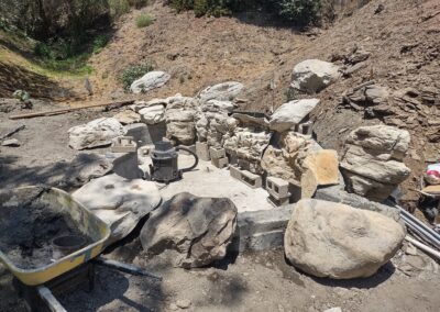 Stone landscaping in progress, featuring rock formations and construction materials.