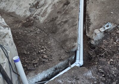 Excavated area with new white PVC pipes installed for drainage or plumbing system.