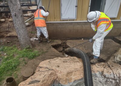 Workers in safety gear repairing a drainage system at a construction site.
