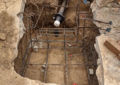 Excavated site with rebar framework and plumbing pipe ready for concrete foundation installation.