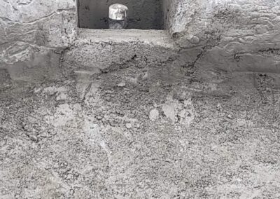Freshly poured concrete with a concrete block and drainage pipe in construction area.