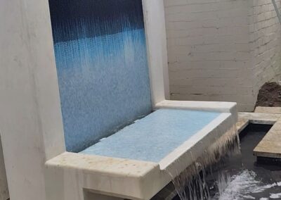 Modern outdoor water feature with cascading water and colorful tile design.