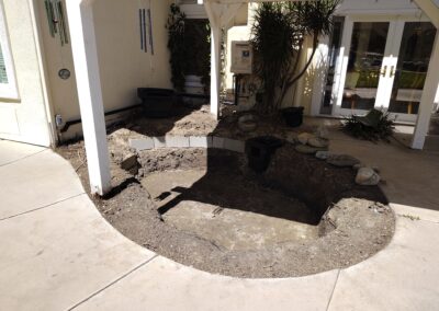 Excavated garden area with rocks, ready for landscaping near a house.