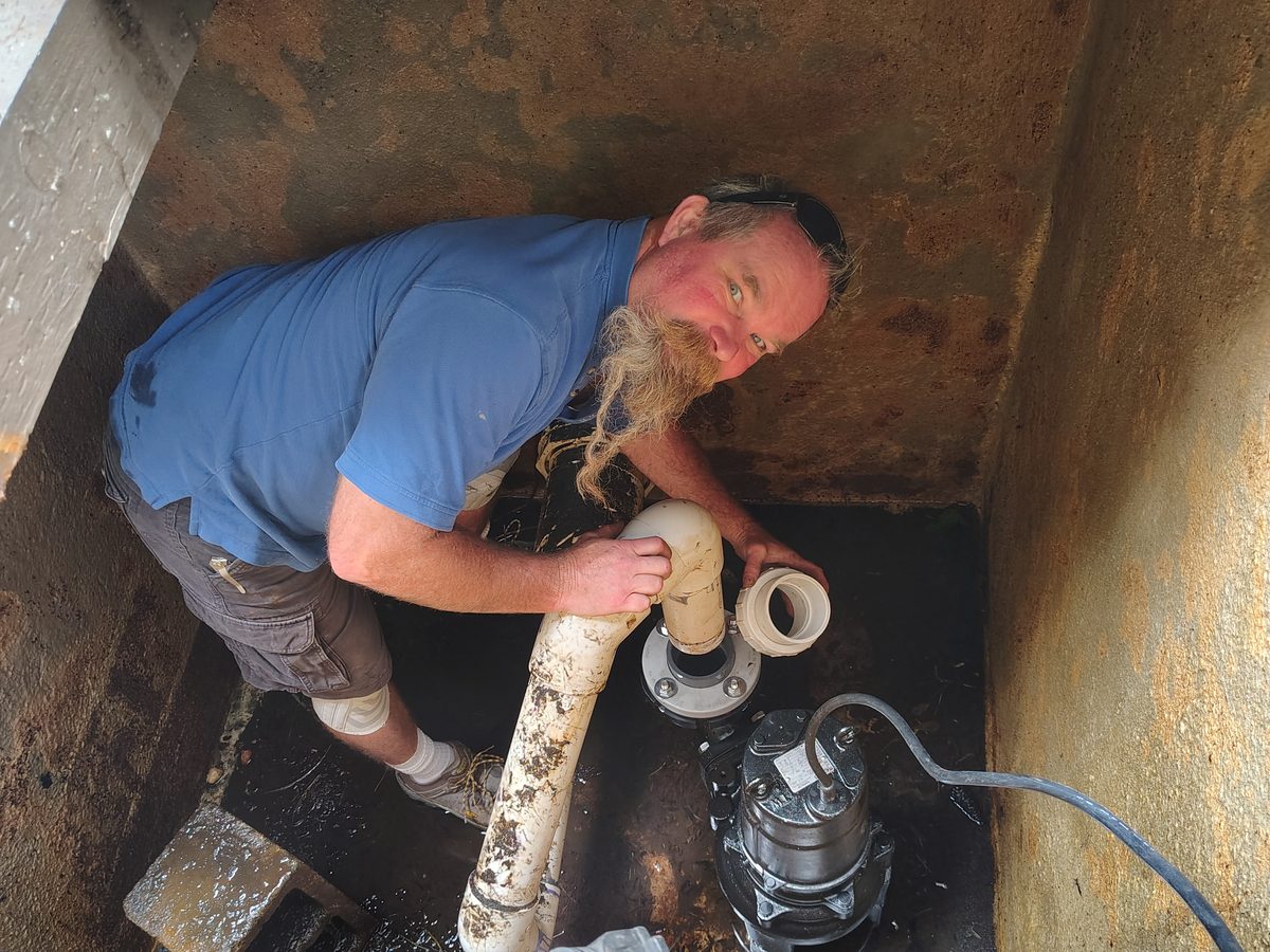 Technician replacing a pond pump in a pump vault